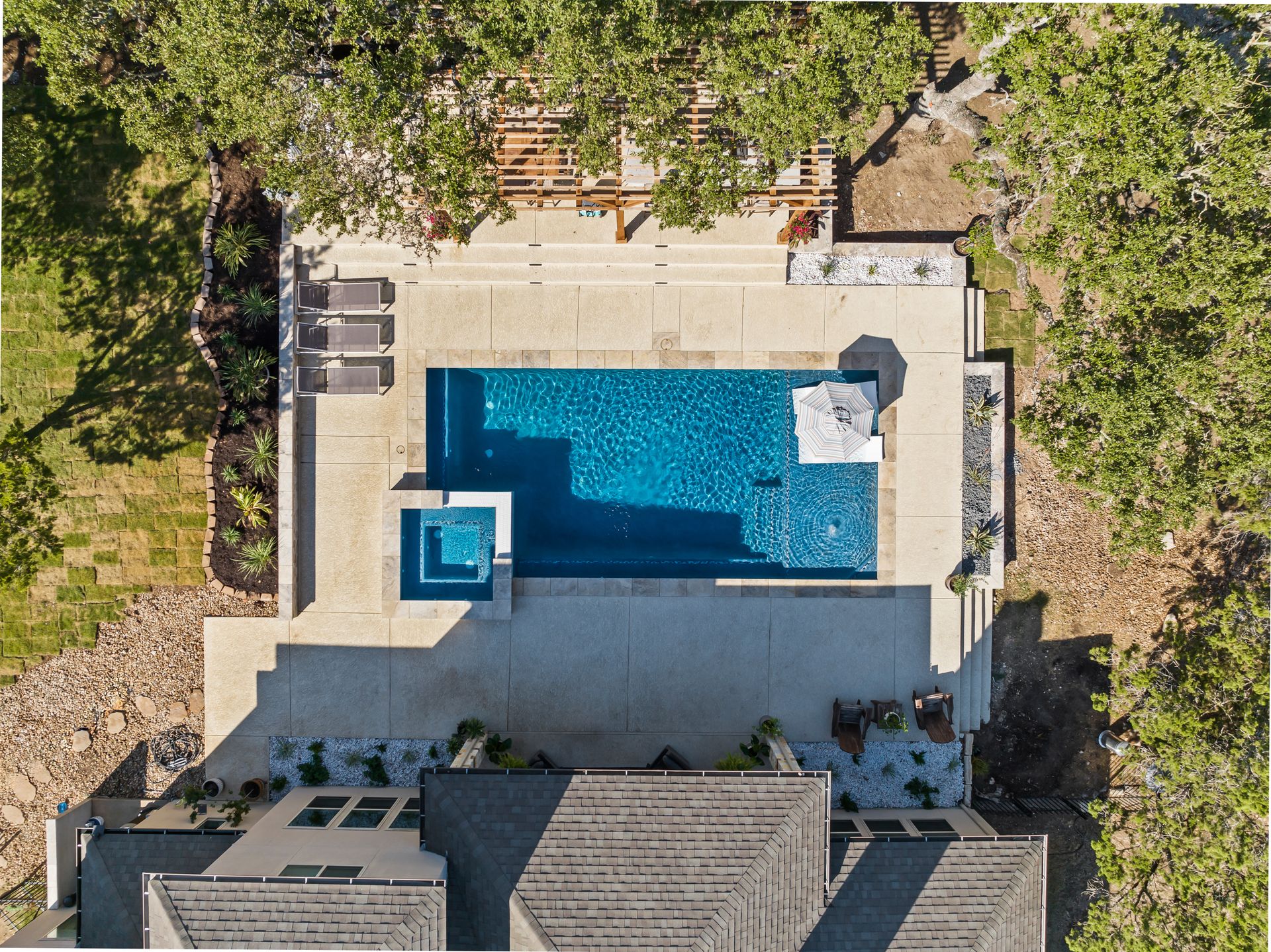 Aerial view of a travertine pool deck surrounding a gunite pool and spa