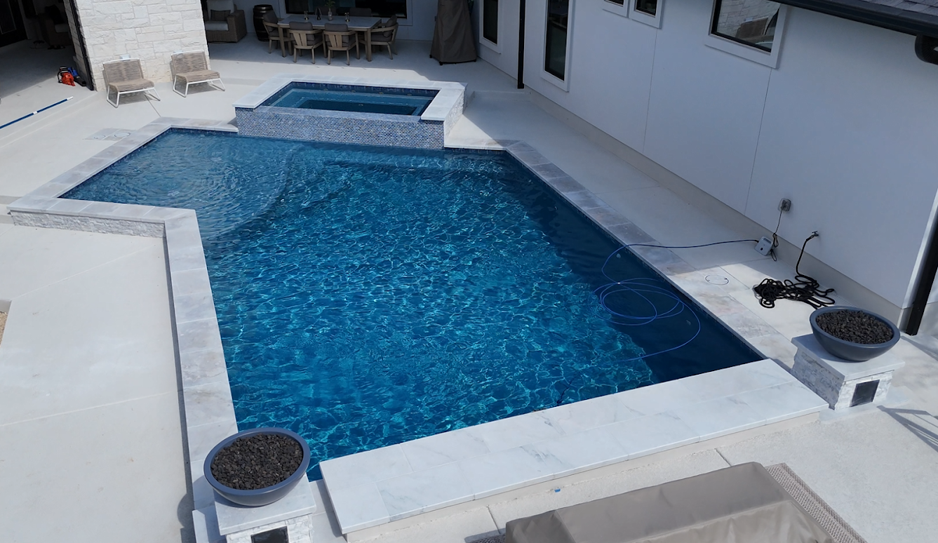 Aerial view of custom freeform gunite pool with dark PebbleTec finish and stone coping in Esperanza, Boerne TX