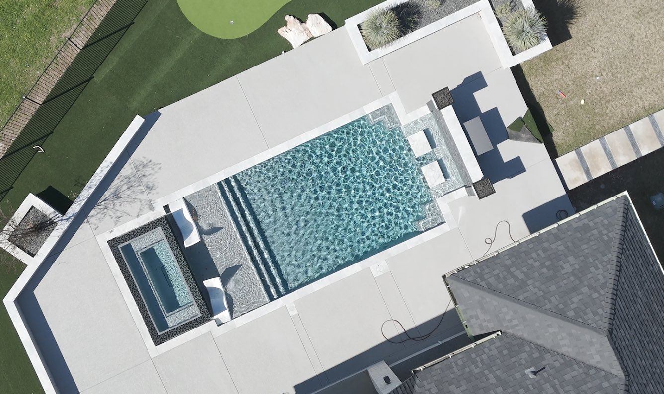 Aerial view of a custom rectangular gunite pool with raised spa and tanning ledge in a Hill Country neighborhood built by J. Oliver Pools