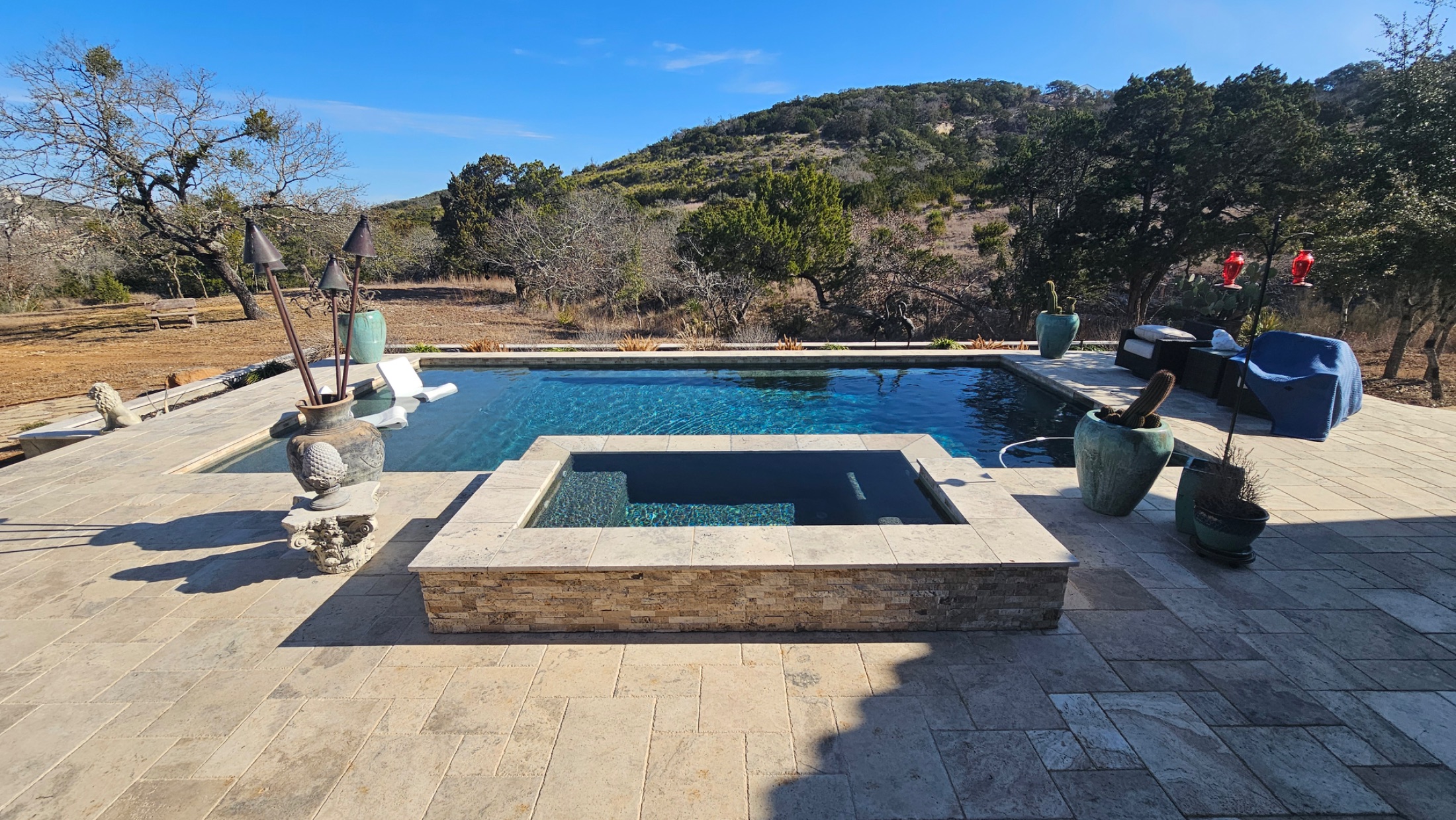 Custom infinity-edge gunite pool with sun shelf and spa built by J. Oliver Pools overlooking the Texas Hill Country near Canyon Lake