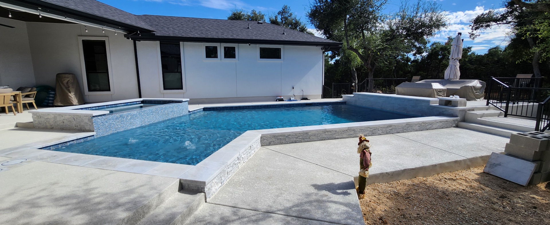 Custom gunite pool with raised spa and stacked-stone coping built by J. Oliver Pools near San Marcos, Texas