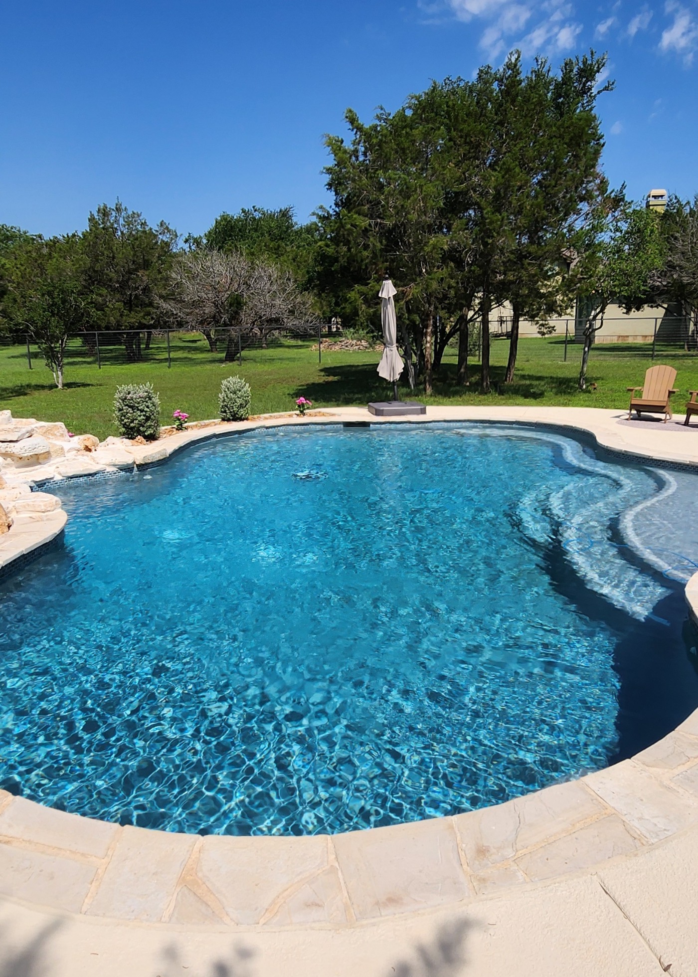 Freeform custom gunite pool with natural stone waterfall built by J. Oliver Pools in Schertz & Cibolo, Texas