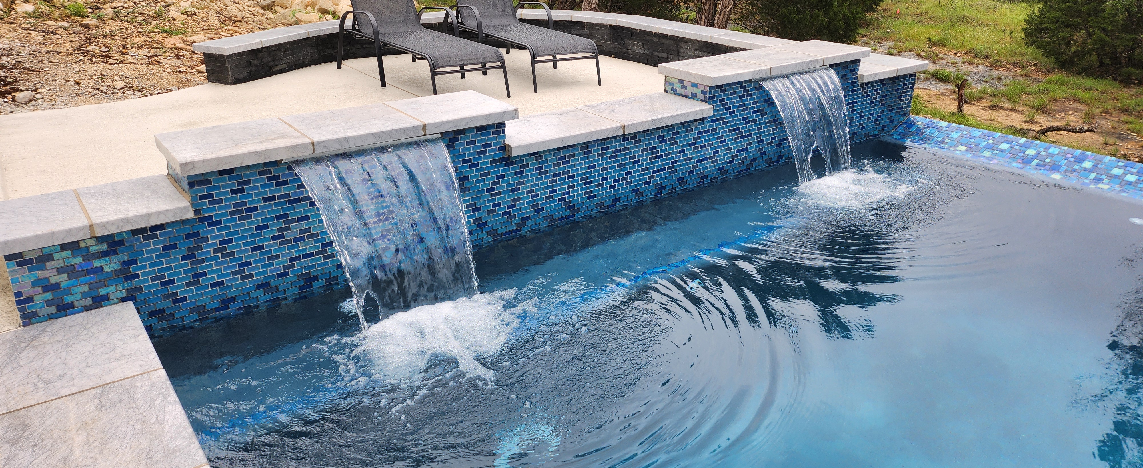 Custom gunite pool with twin glass-tile spillways overlooking the Hill Country in Windsong, Boerne TX