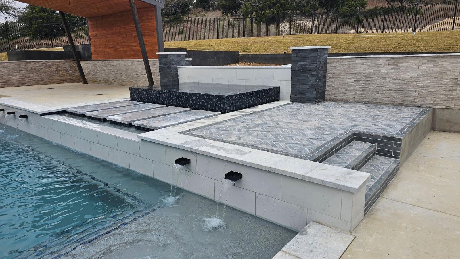 Poolside outdoor living pavilion with dining area beside a custom pool