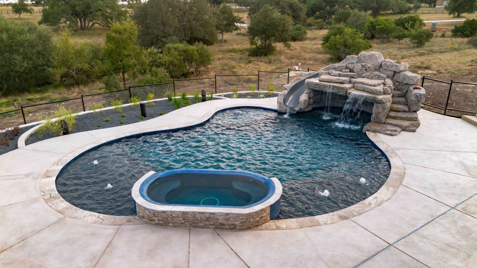 Aerial view of a custom geometric pool and covered outdoor living pavilion built by J. Oliver Pools in New Braunfels, Texas