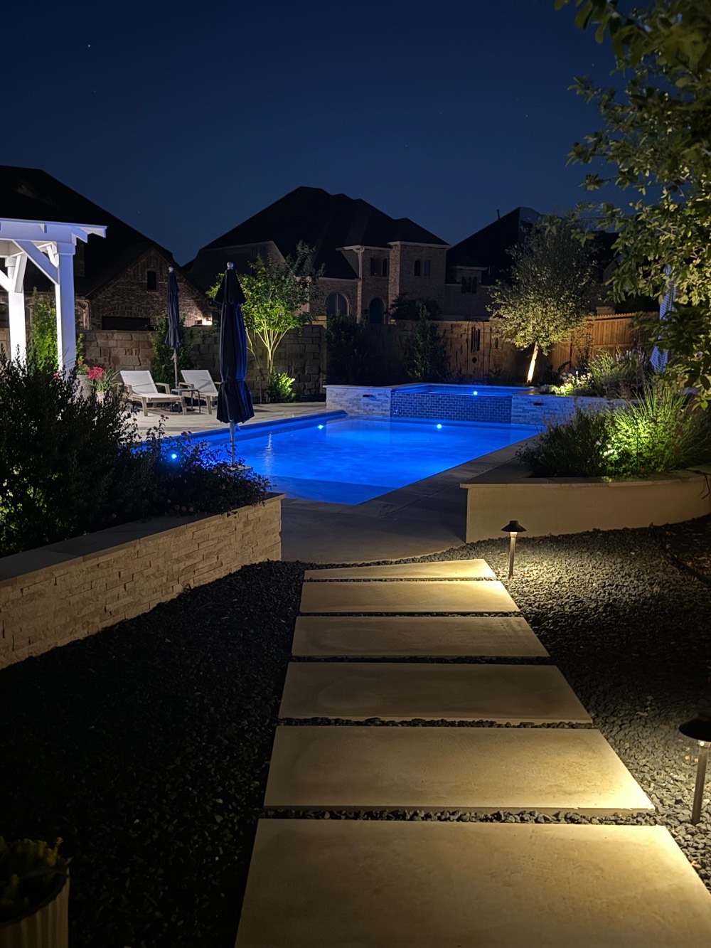 Poolside decking with outdoor dining and kitchen area in a Hill Country backyard