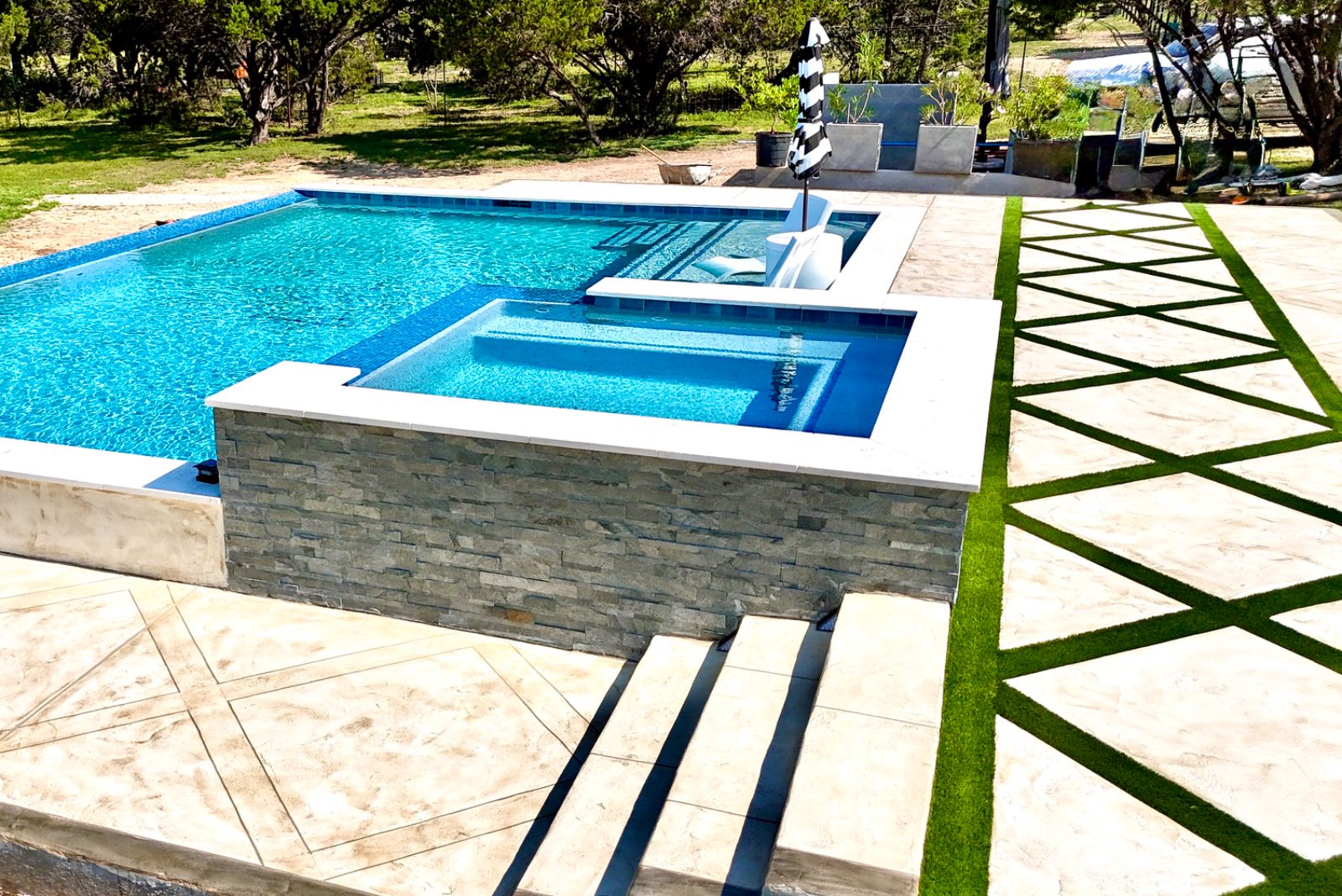 Raised spa with stone spillway flowing into a custom gunite pool, built by J. Oliver Pools in New Braunfels, Texas