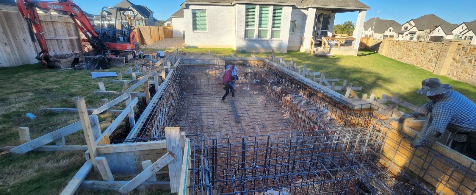 Crew tying steel reinforcement in the excavated pool and spa shell in Veramendi, New Braunfels TX, before the gunite shoot